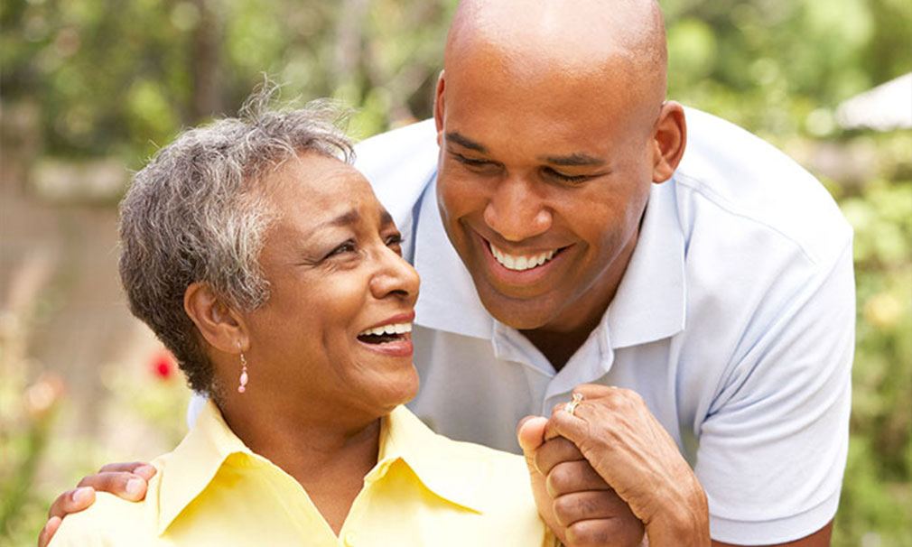 Female wearing a yellow shirt holding a man's hand who is wearing a blue shirt.